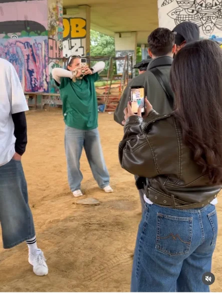 Two people filming each other with a phone during a street shoot.