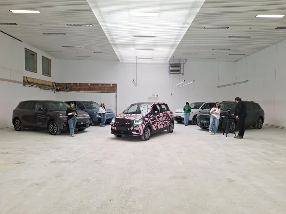 A studio set with several electric cars, one wrapped in a floral livery.