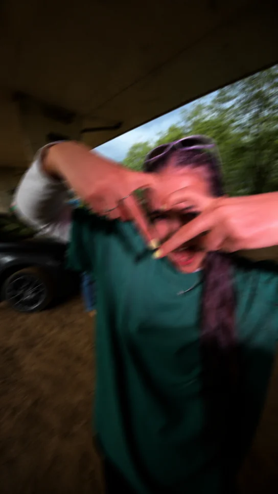 A creator in a green t-shirt frames the camera with her hands during a shoot.