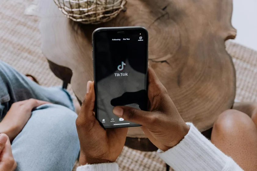 Hands holding a smartphone playing a video in a social media feed.