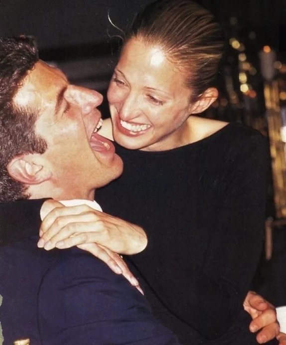 Deux invités enlacés éclatent de rire devant l'objectif, lors d'une soirée des années 1990.